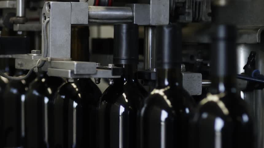 The machine is putting caps on the wine bottles