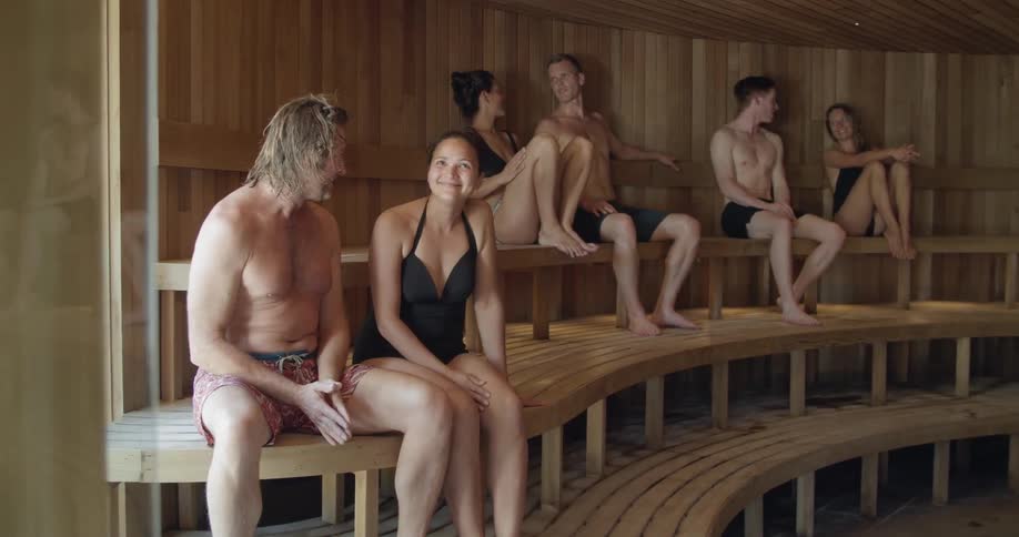 Three white females and three white males are sitting in a sauna relaxing and talking