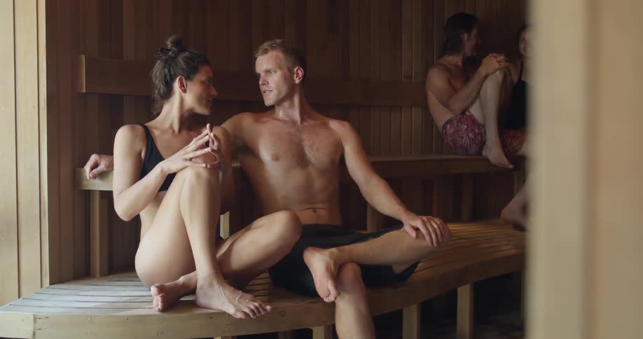 A man puts his arm around his girlfriend in a sauna