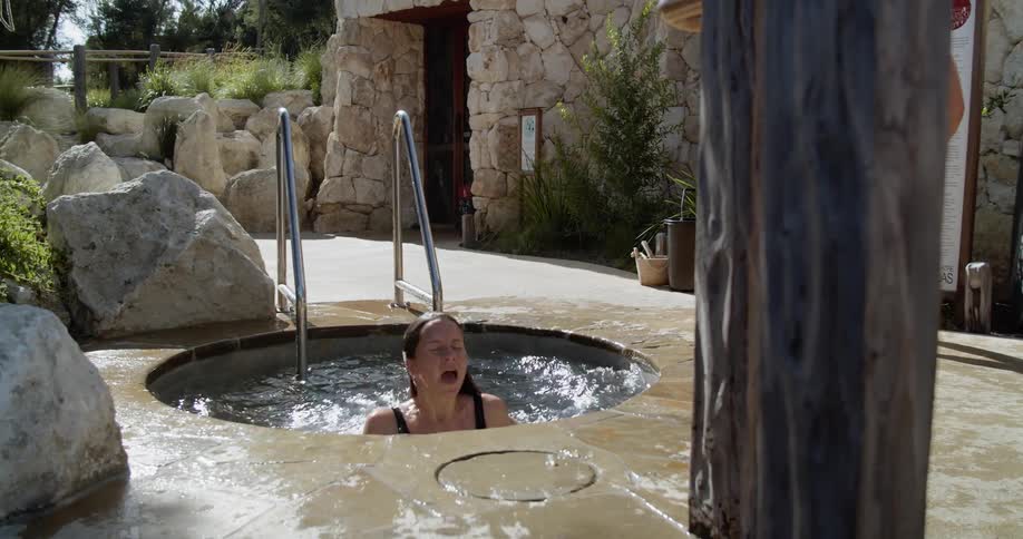 A woman jumps into an outdoor hot tub