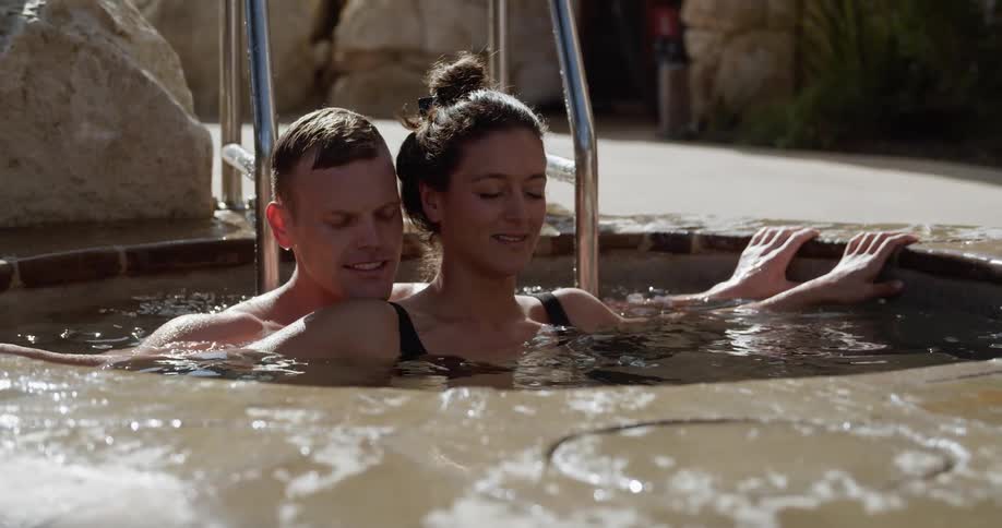 A man and woman sit in a hot tub together