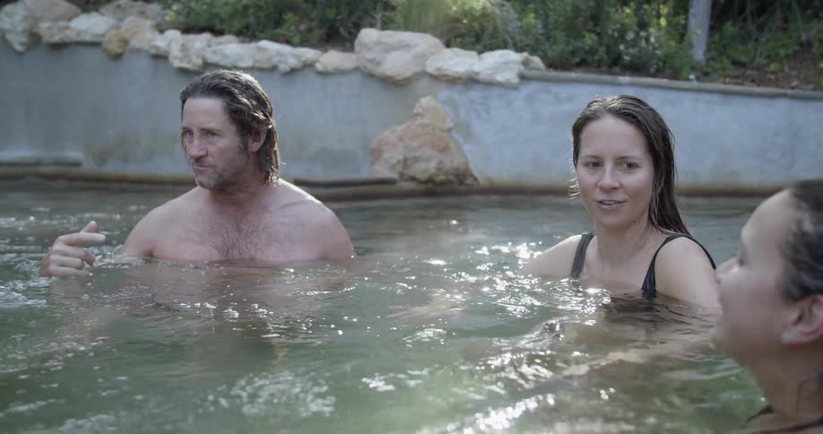 Man soaks in outdoor bubbling pool with friends