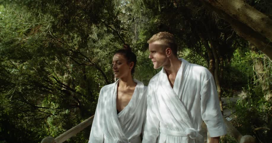 A man and woman in bath robes walking through a botanical garden
