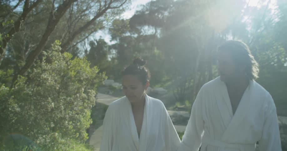 Couple wearing karate gi walk through park holding hands