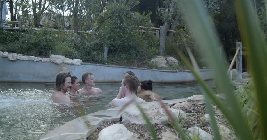 A group of men and women sit in a hot tub