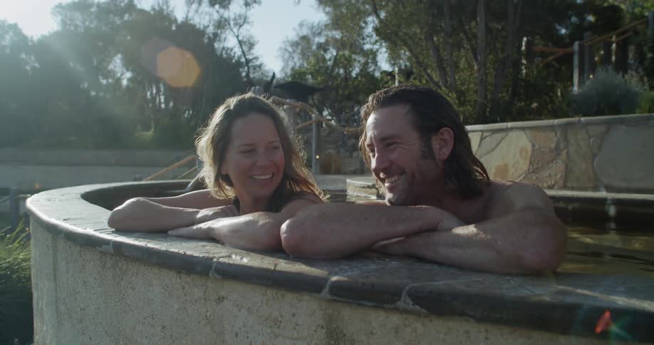Couple relaxing and laughing in an outdoor hot tub at a spa