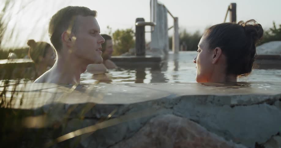 A man and woman sit in a hot tub and talk