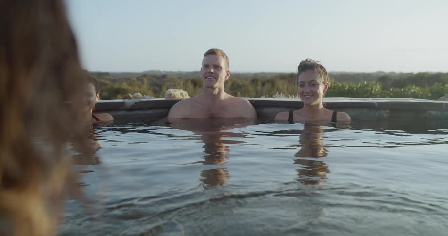 A group of people sit in a hot tub outside