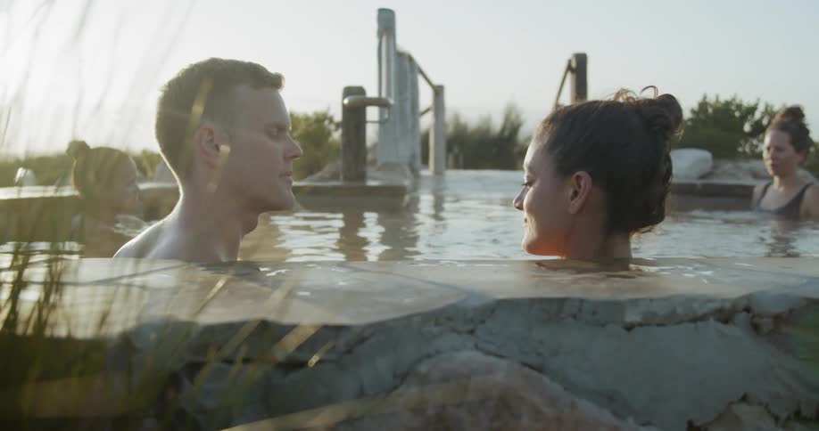 People relaxing in a kind of thermal bath surrounded by bushes