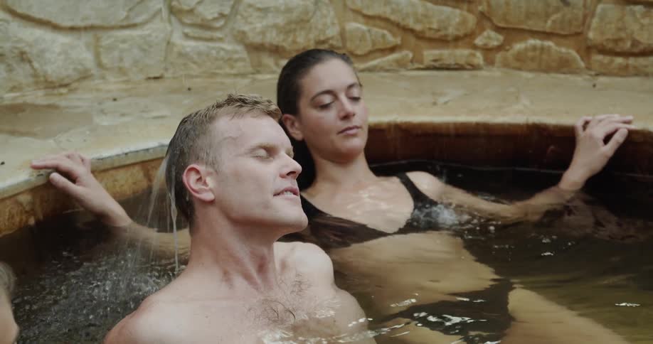 People relaxing in a bath spa as water falls onto them