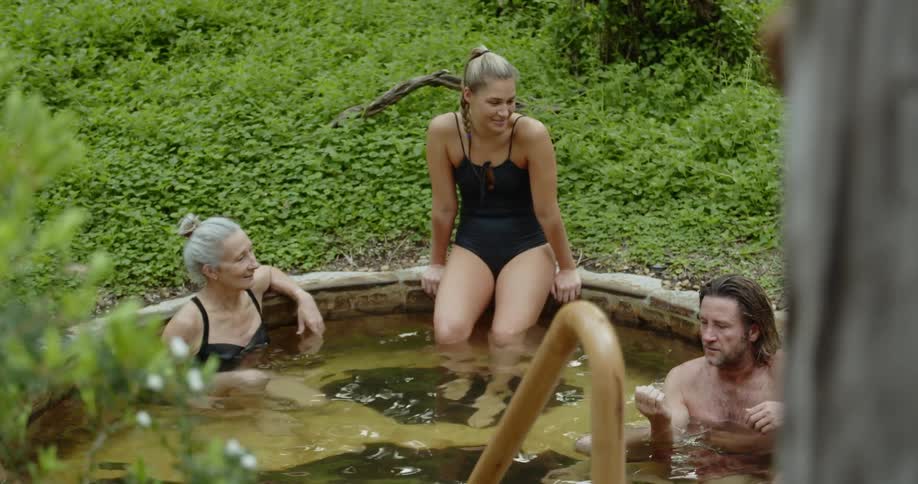Three people relax and talk while sitting in a bath spa
