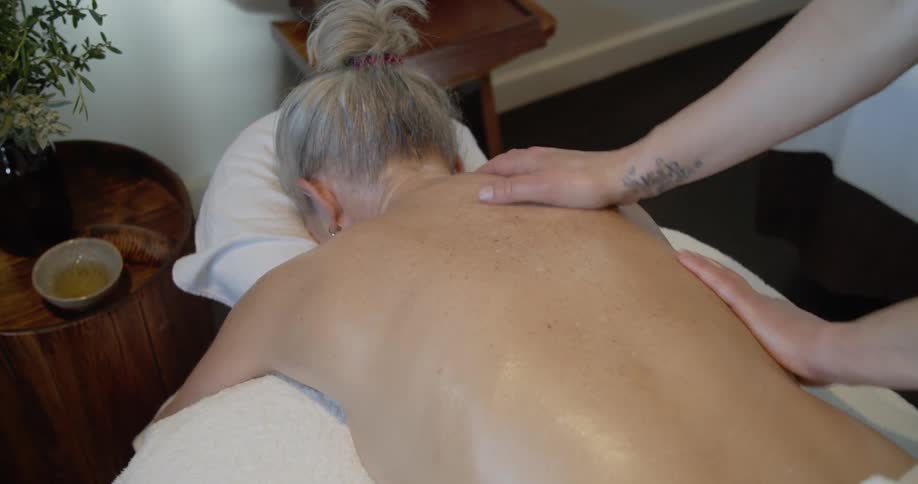 Female masseur massages for blonde womans back at spa center