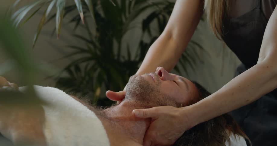 Female masseur massages mans shoulders at spa center