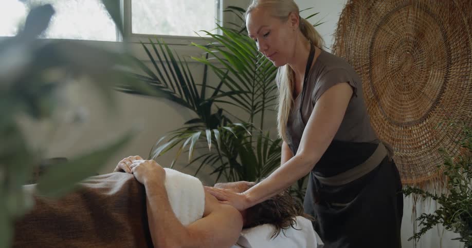 Female masseur massages mans shoulders at spa center