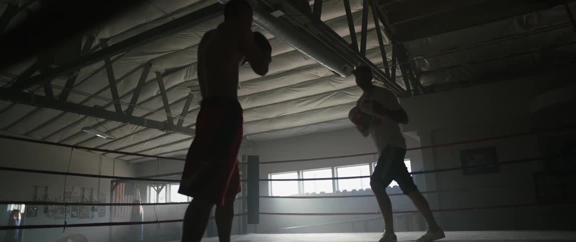 Two fighters are fighting in a dark gym