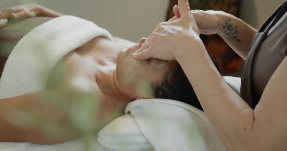 Woman massages lotion onto another womans face