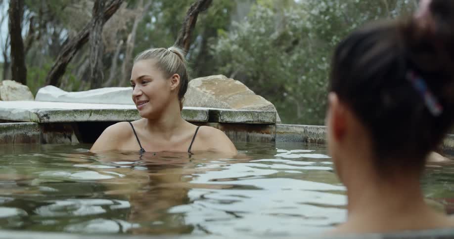 Two women sit in an outdoor hot tub together