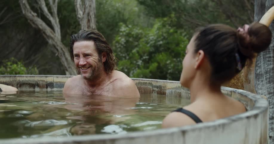 People relaxing in a kind of thermal bath surrounded by bushes