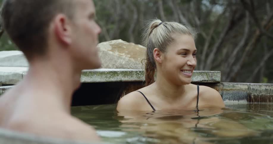 People relaxing in a kind of thermal bath surrounded by bushes