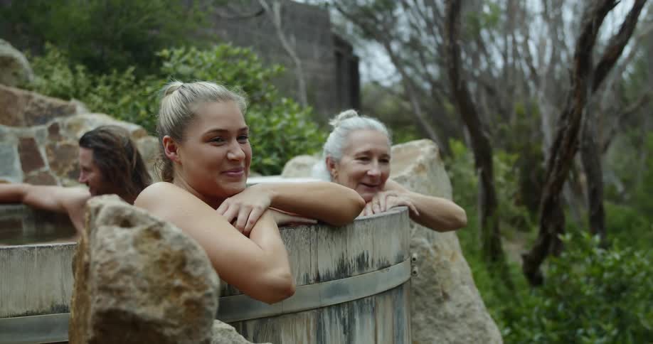 A group of people smile and talk as they soak in an outdoor spa