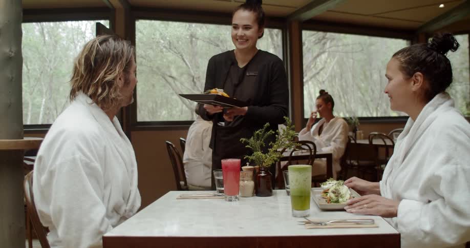 Couple wearing robes being served in a restaurant at a spa