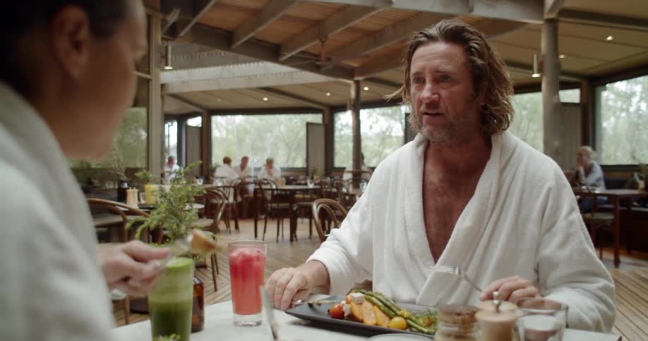 A couple in white robes is eating a meal and drinking smoothies in a restaurant