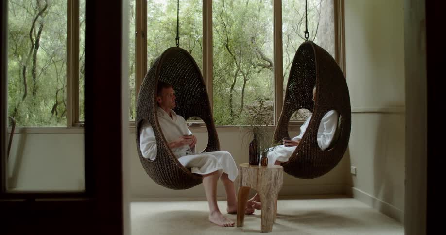 Two people sit in hammock chairs at a resort