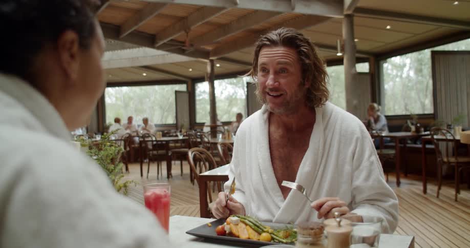 Two men eat a meal together wearing robes