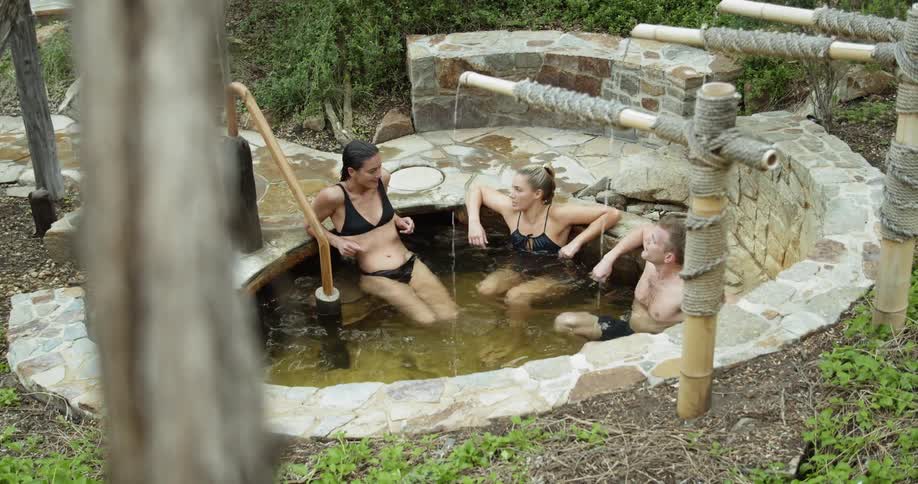 People relaxing in a kind of thermal bath surrounded by bushes
