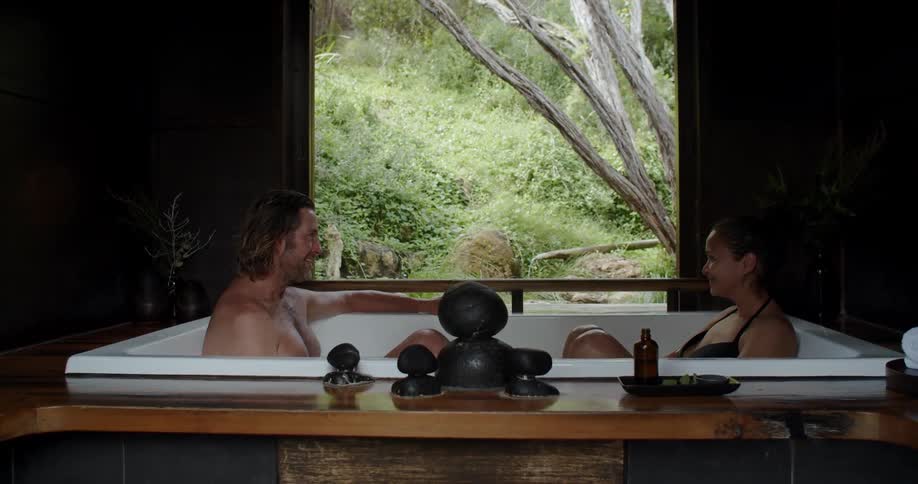A man and woman sit in a bathtub and talk