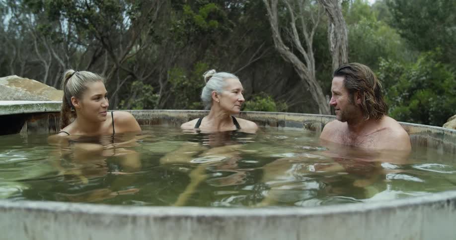 A group of people relaxing in a kind of thermal bath surrounded by trees