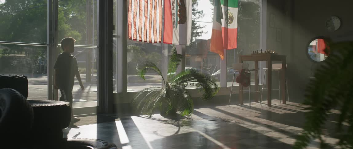 A boy walks into a storefront on a sunny day