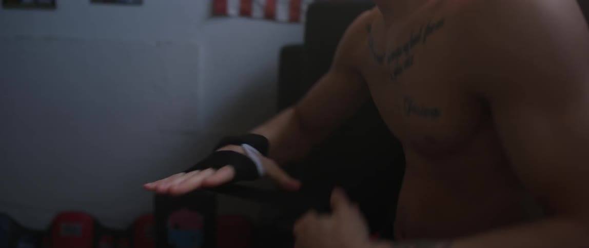 A boxer sitting in a gym and wrapping his hand