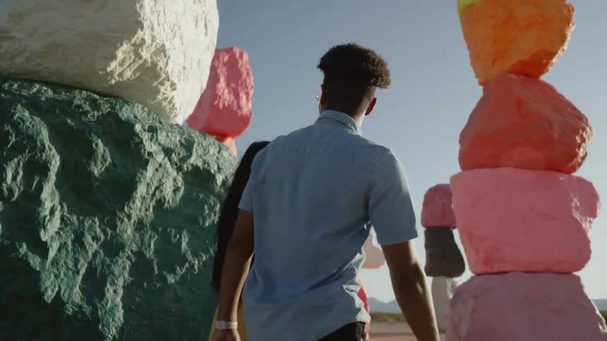 People tour past stacks of painted stones