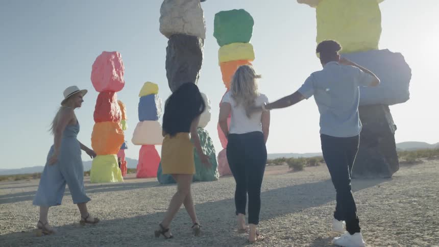 Three women and a man walked towards large colorful rock sculptures