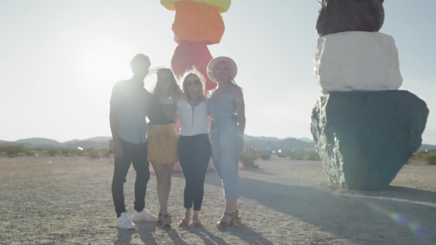 A group of people stand in the desert surrounded by structures made of colored rocks