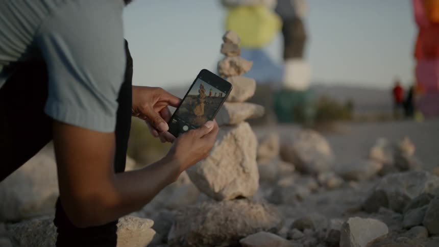 Man photographs small stacked rocks mimicking larger stacked rocks