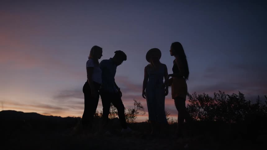 Group of people gather in wilderness after dusk
