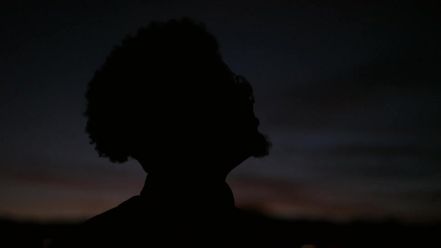 A black man looks up into the night sky