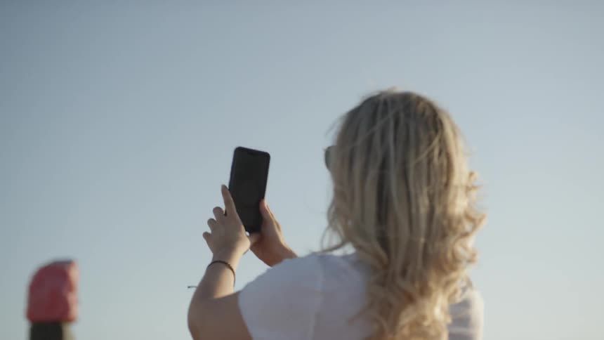 A young woman takes a picture of colorful statues
