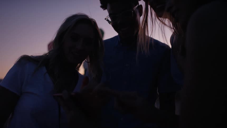 A group of people are gathered outside at dusk