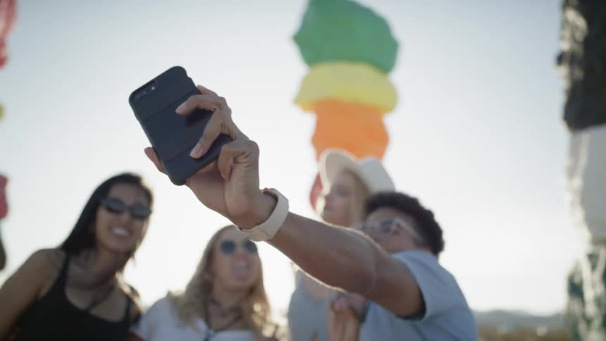 Three women and a man take a picture on a smart phone with colorful rock monuments in the background