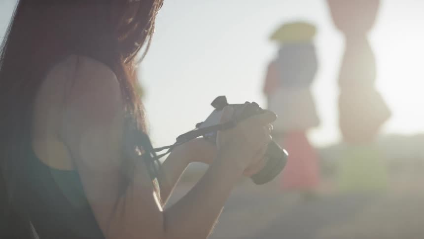 A woman photographs the stacked painted rocks in the desert