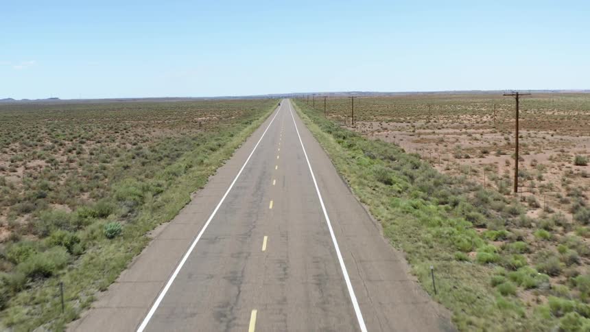 A paved road running through a rural area and stretching off far into the distance