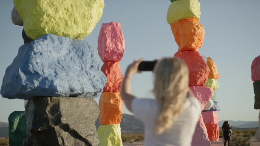 A woman uses her cell phone to take pictures of colored rock formations