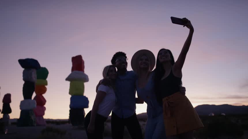 A woman holds up a cell phone to take a selfie of herself and friends