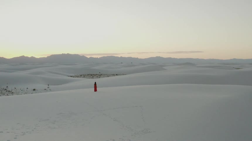 A woman in a red dress is walking on the field