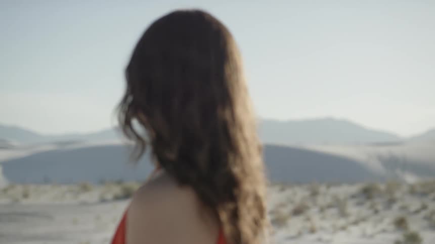A woman standing in the desert with mountains in the background