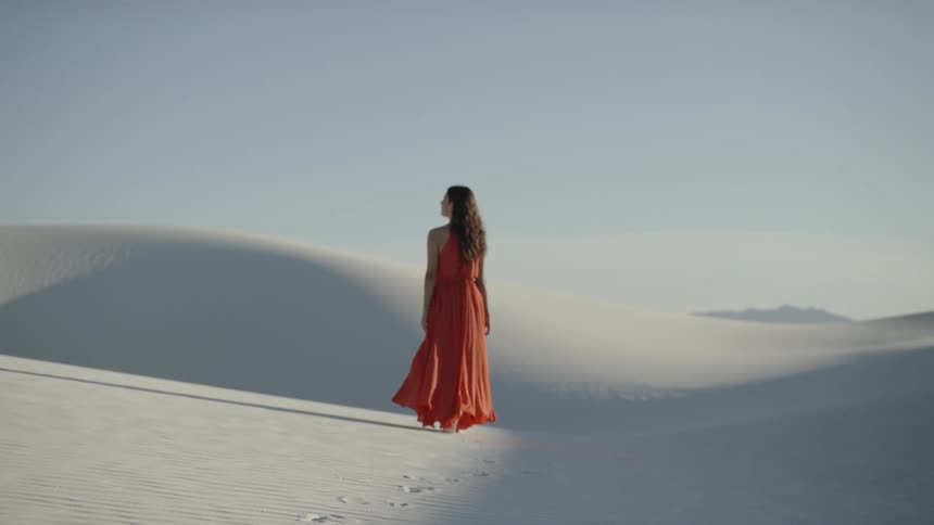 Woman walks among white sand dunes