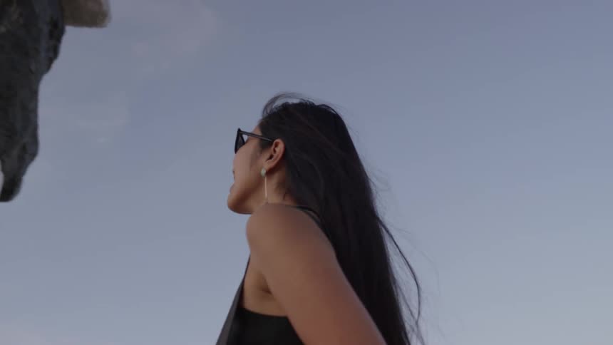 A woman with shades standing outside looking at large multicolored rock monuments